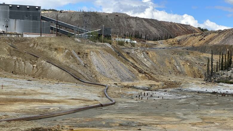 A view of an abandoned mine site with a milling facility visible on a hill.