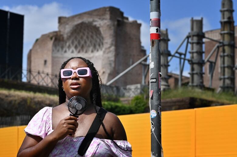 A person holds up a handheld fan to their face.