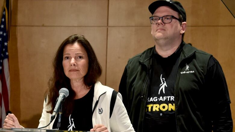 National Executive Director and Chief Negotiator Duncan Crabtree-Ireland looks on as SAG-AFTRA President US actress Fran Drescher (L) speaks during a press conference at the labor union's headquarters in Los Angeles, California, on July 13, 2023. Tens of thousands of Hollywood actors will go on strike at midnight Thursday, effectively bringing the giant movie and television business to a halt as they join writers in the first industry-wide walkout for 63 years. The Screen Actors Guild (SAG-AFTRA) issued a strike order after last-ditch talks with studios on their demands over dwindling pay and the threat posed by artificial intelligence ended without a deal. (Photo by Chris Delmas / AFP) (Photo by CHRIS DELMAS/AFP via Getty Images)