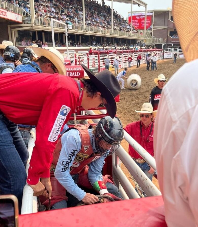 A man wearing a helmet is in a preparation area for a bull ride.