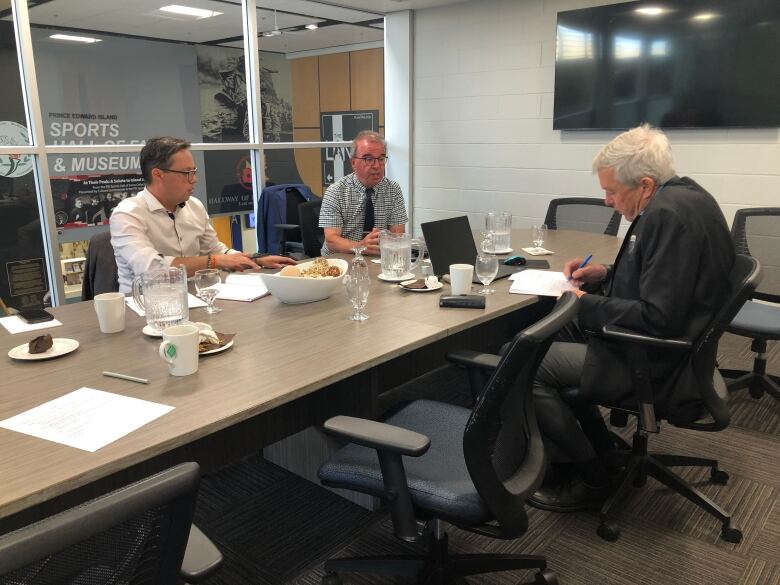 Kutcher, Brown and Ogden sit around a table taking notes.