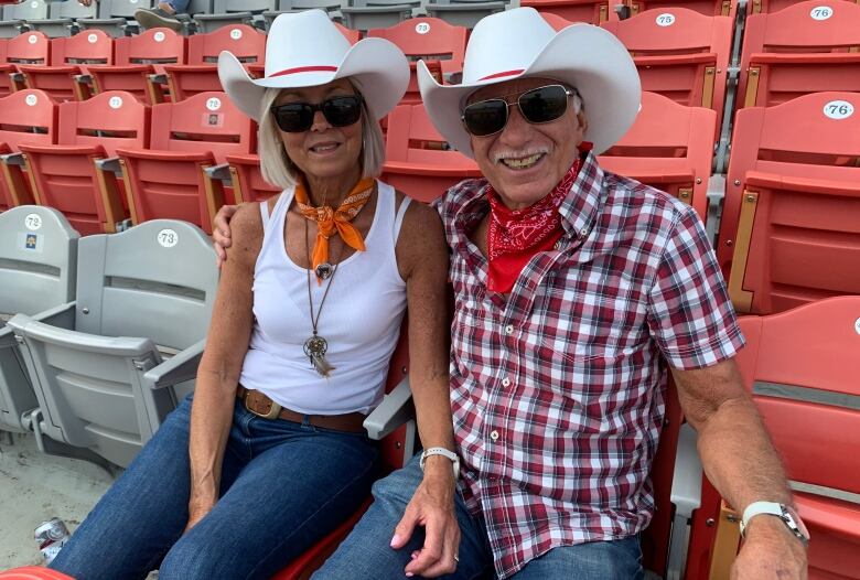 Two people wearing cowboy hats smile for the camera.