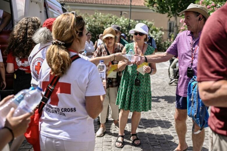 Volunteers pass out water bottles to senior citizens.