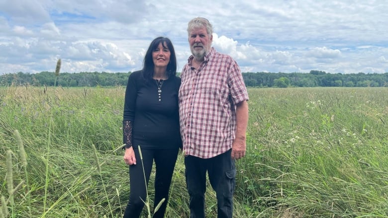 Two people stand in a field.