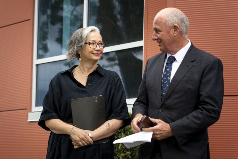 A woman and man stand next to each other, smiling.