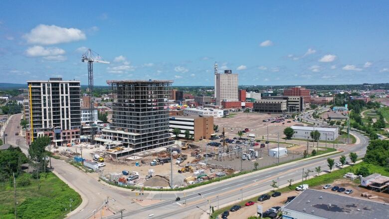 A tower crane between two partially finished buildings with several other taller buildings in the background.