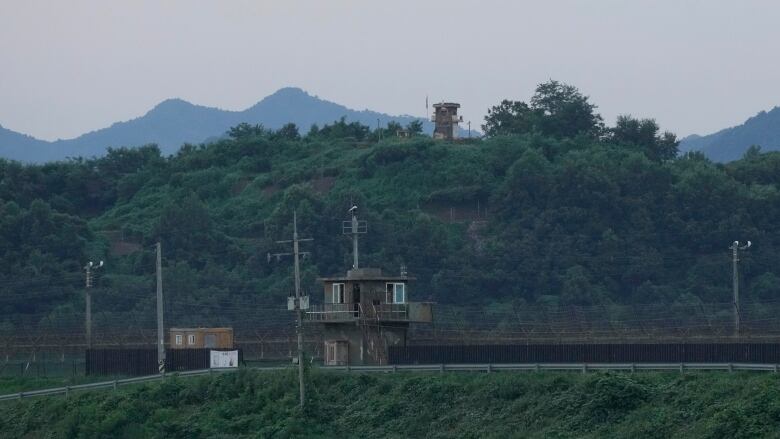 Buildings and a tower are shown in a forested area.