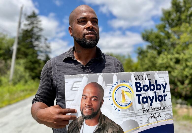 A bald man holds an election sign.