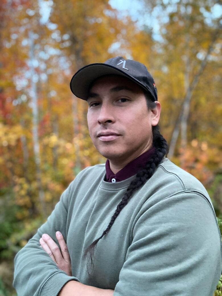 A man with his arms crossed, wearing a baseball cap.