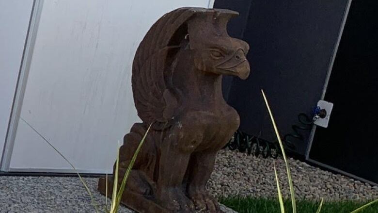 A close-up of a griffin statue on a front lawn.