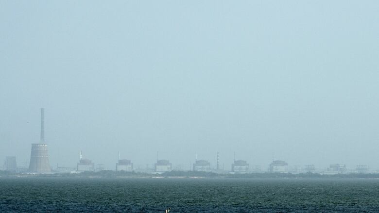 A nuclear power plant is seen on a hazy day across a river.