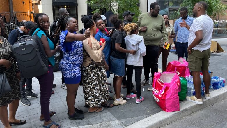 A group of asylum seekers stand in line on a Toronto sidewalk. 