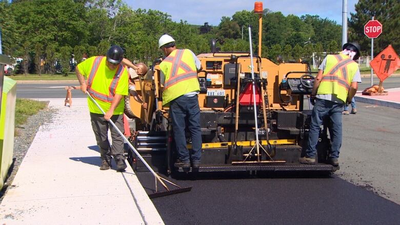 A group of road workers laying asphalt. 