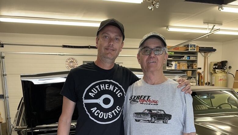 Doug's left arm is on  his father's right shoulder. There is a black 1969 Nova L78 and a lime green 1969 GTO RAIII behind them.