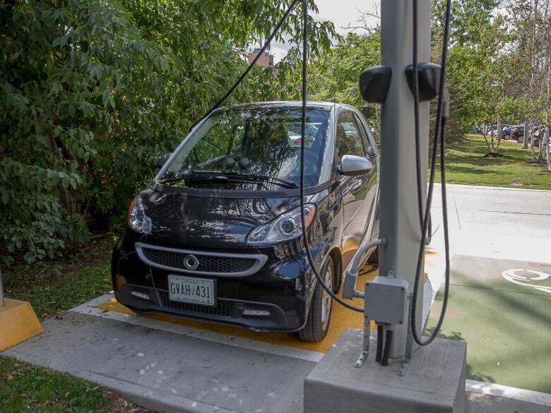 A small electric car is plugged into a charging station in Toronto. 