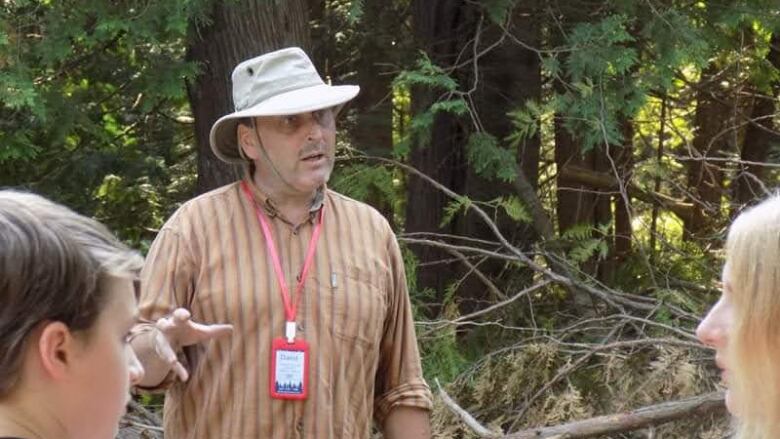 A man gestures while teaching a wilderness survival class.