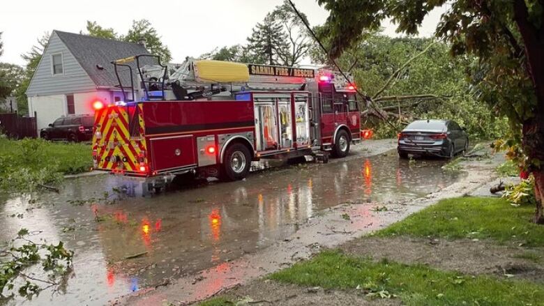 A firetruck is shown in front of downed trees and a power line.