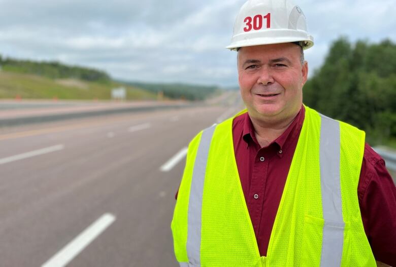 A man with a helmet stands on a highway.