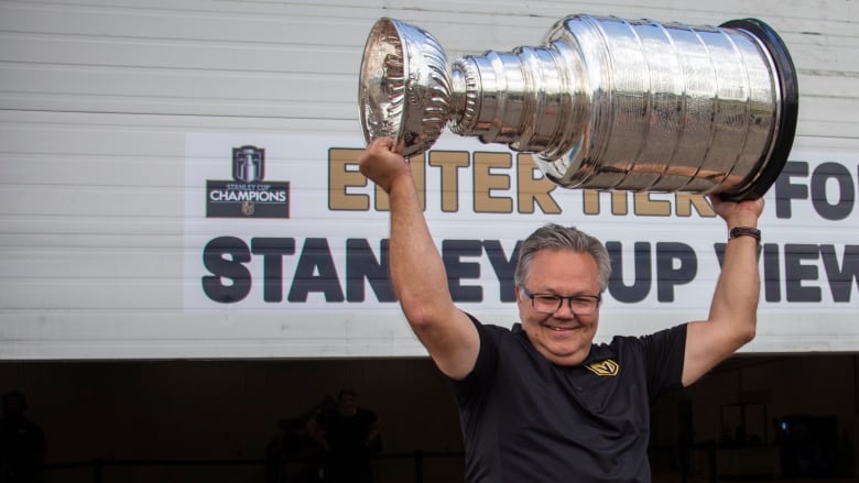 A man holds the Stanley Cup over his head.