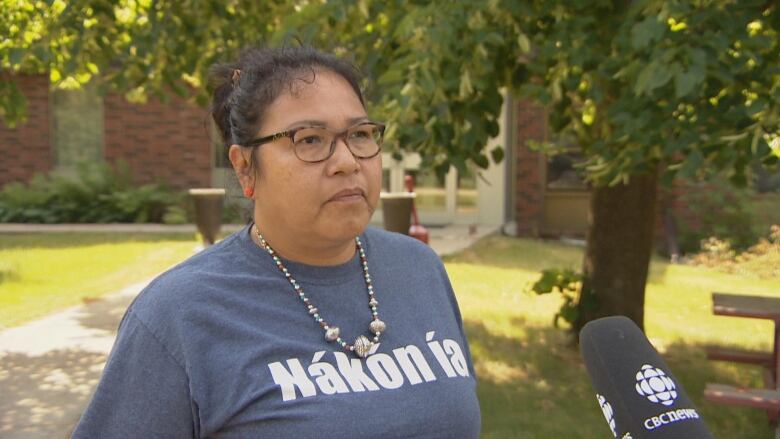 Terrina Bellegarde in front of the Carry The Kettle band office wearing a shirt that says Nakon ia