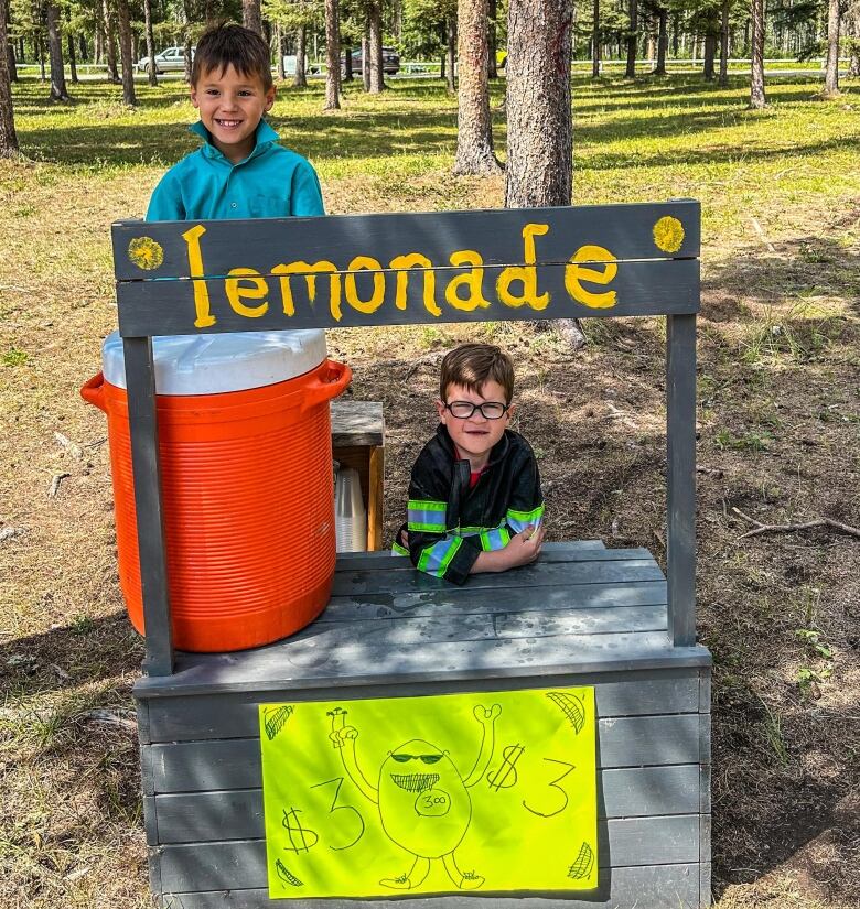 Two small boys at an outdoor lemonade stand.