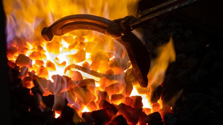 A horseshoe is pulled from a fiery forge.