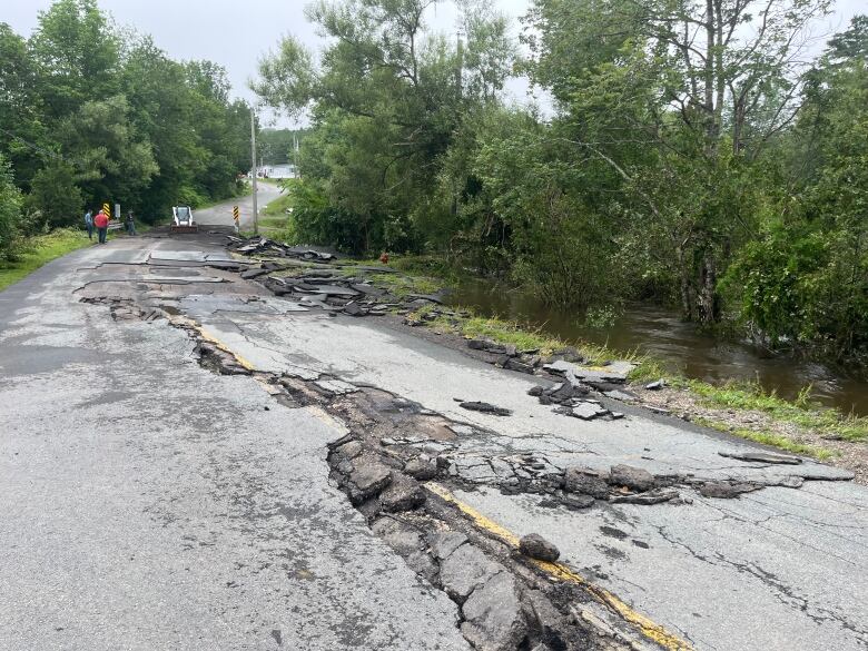 A damaged road with water at its edge.