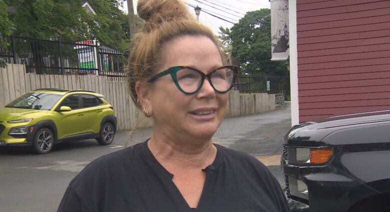 A woman in a black top speaks with a reporter.