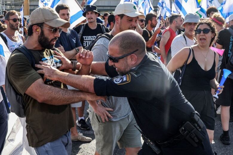 A police officer pushes a man.