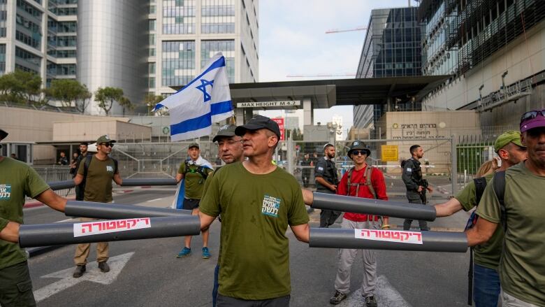 People in military garb link arms during a protest on a road.