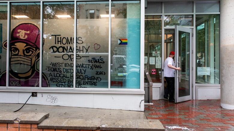 A man enters a door with a colourful mural that says 'Thomus Donaghy OPS.'