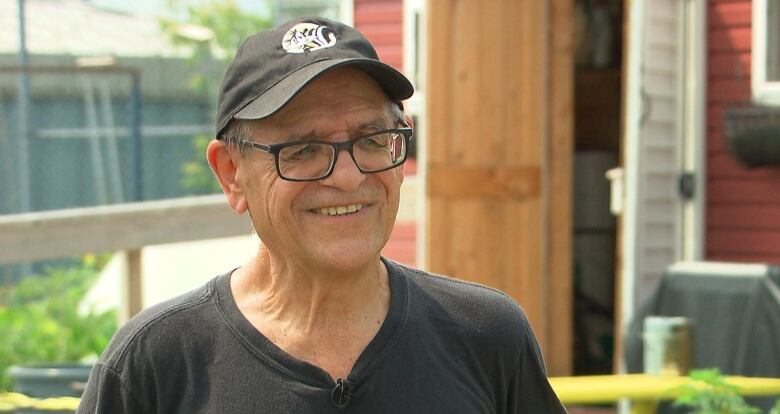 Smiling man in a baseball cap and black-rimmed glasses.