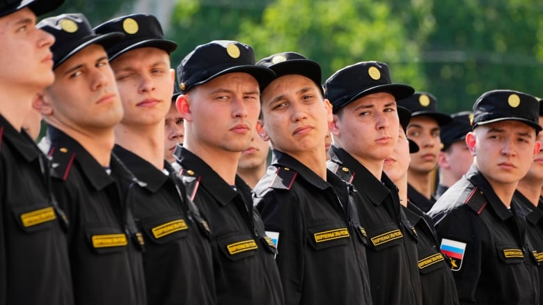 People in military garb look right while standing in a line.