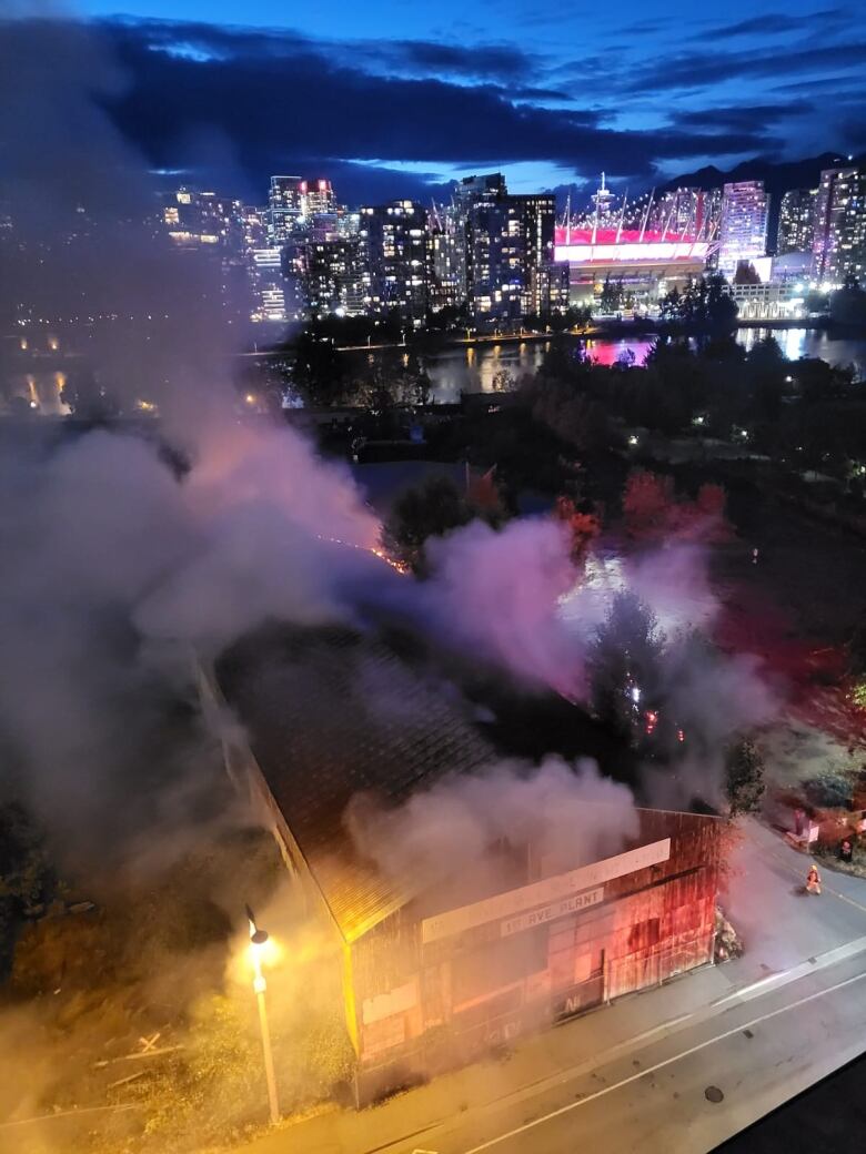 Smoke arises from a building, with the downtown Vancouver skyline in the background.