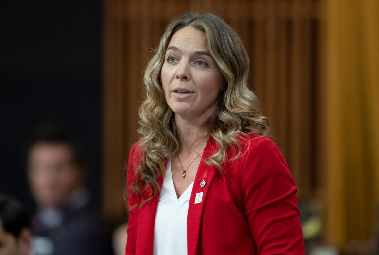 MP Jenna Sudds rises in the House of Commons. She's wearing a red blazer and white blouse.