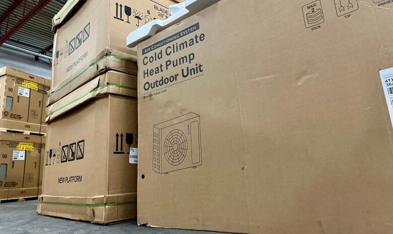 Boxes of heat pumps are piled up in a warehouse.