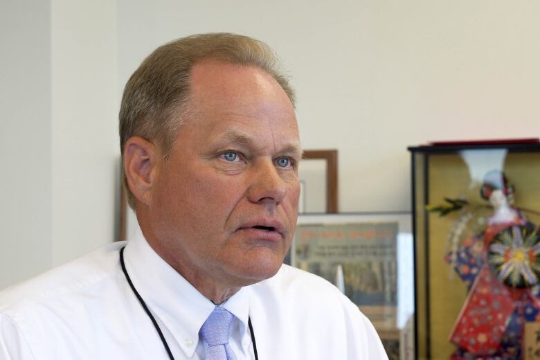 A middle-aged man in a white shirt and tie.