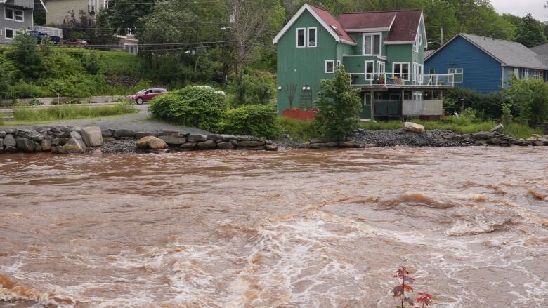 An image of flooding waters with houses in the background.