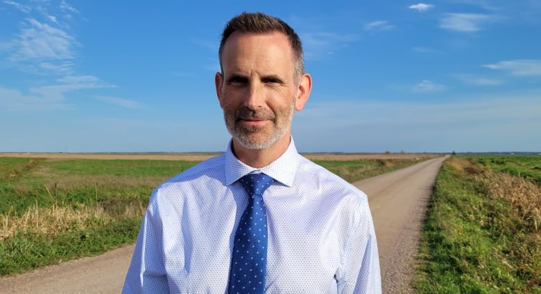 Man standing in field, wearing tie