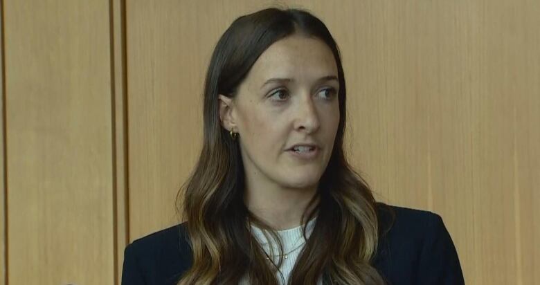 A woman with long brown hair is speaking. 