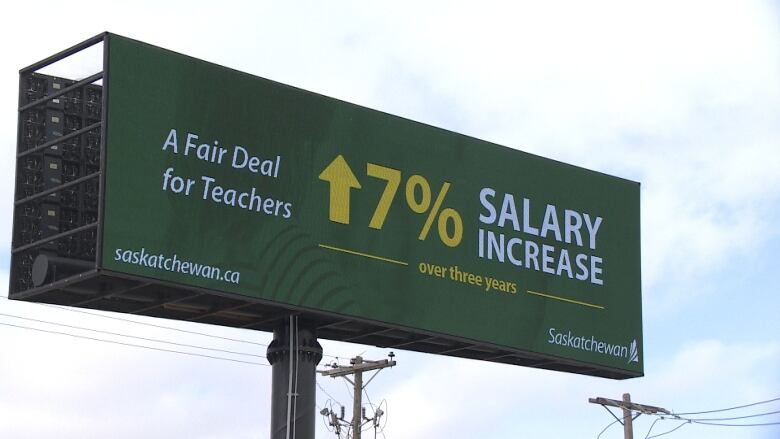 A billboard can be seen saying 'a fair deal for teachers, 7 per cent salary increase over three years' 