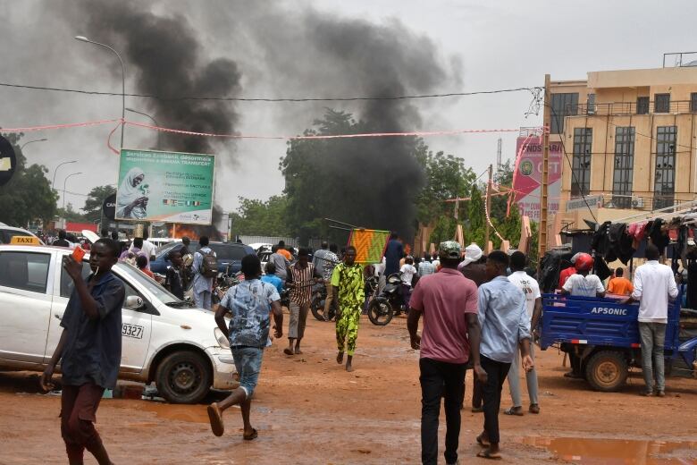 Black smoke billows behind a crowd of people.