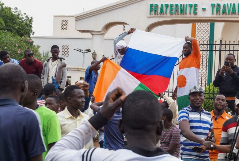 A crowd of people hold up flags.