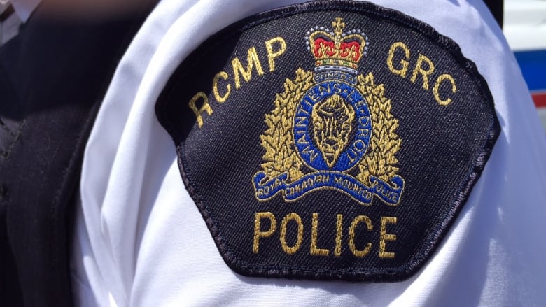 A closeup shows the badge of an RCMP uniform