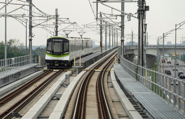 A train on a light rail system heads towards a station.