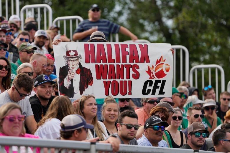 Fans hold up a sign reading 