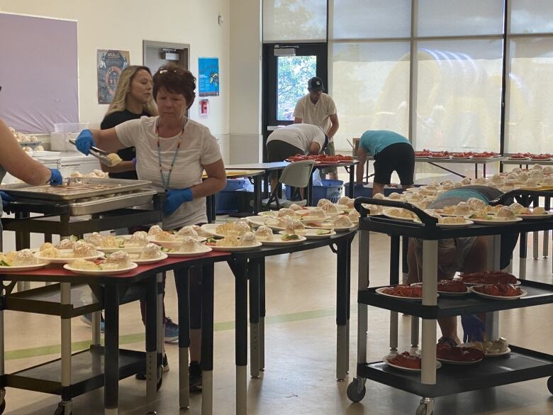 Community members prepare plates of lobster dinner.