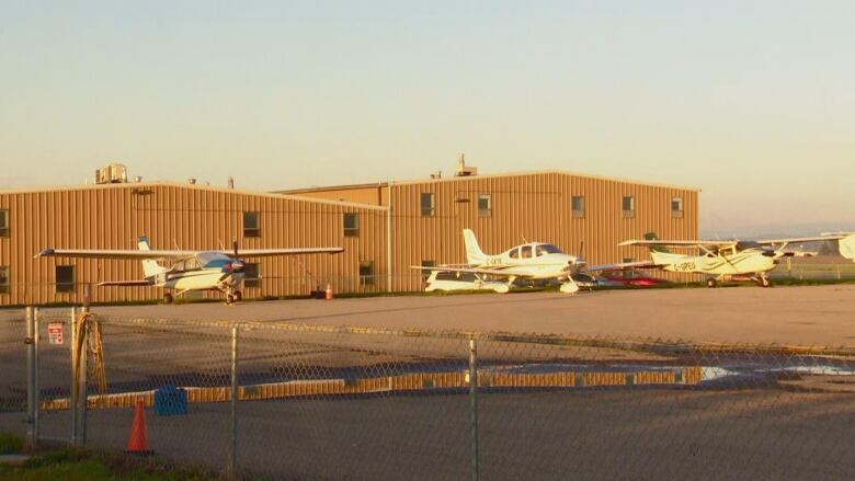 Airplanes parked in front of a brown building. 