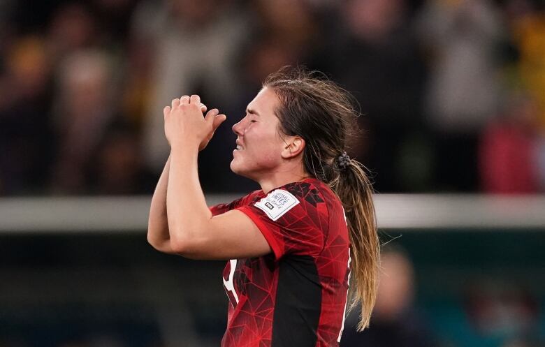 A woman soccer player reacts with disappointment after a loss.