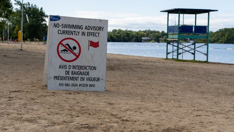 A no swimming sign rests on a beach. 